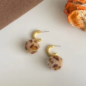 Detailansicht der stilvollen Leoparden Plüsch Bommel Ohrringe mit goldenem Halbkreis Design.