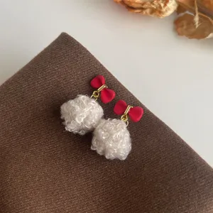 Nahaufnahme von niedlichen weichen flauschigen Pompon Ohrringen mit roten Schleifen Winter.