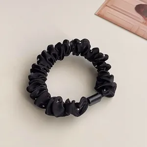 Detailed view of the black pleated hair scrunchie with sparkling rhinestones and buckle.