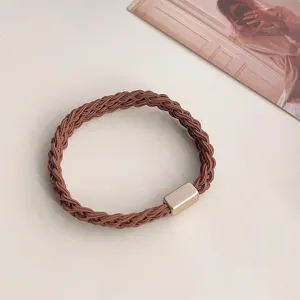 Close-up detail of the brown braided hair tie featuring an elegant metallic rectangular accent.