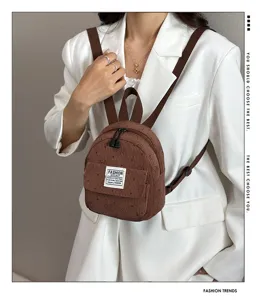 Close-up detail of a brown corduroy mini casual backpack with front pocket and shoulder straps.