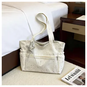 Vista dettagliata della borsa tote bianca con stampa a stelle e ciondolo a stella.