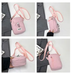 Detailed view of pink nylon crossbody phone bag with front drawstring pocket and shoulder strap.
