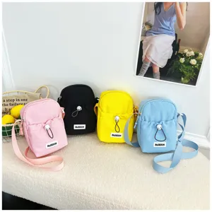 Detailed view of casual solid color crossbody phone bag with drawstring pocket and fashion label.