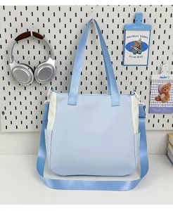 Vue détail du sac cabas en toile bleu clair montrant un design bicolore et large.