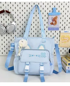 Detail view of the light blue canvas shoulder bag featuring cute cat ears and plush charm.