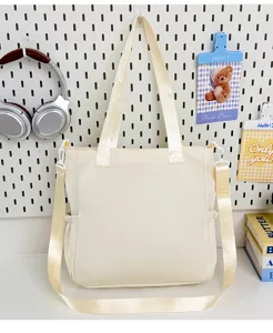 Detail view of casual beige canvas tote bag with adjustable strap and side pockets in daily scene.