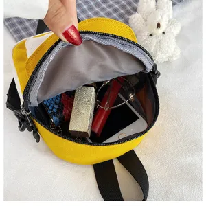 Yellow canvas mini backpack detail shot, showing spacious interior capacity with plush bear charm.