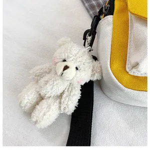Close-up detail of a cute white plush bear keychain with a black strap and canvas bag.