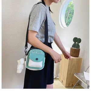 Detail view of a cute canvas crossbody bag featuring a contrast flap and cute bear pendant charm.