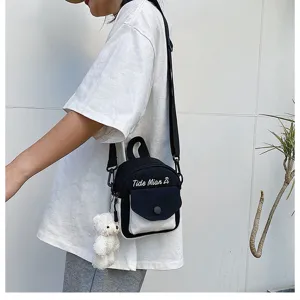 Detail shot of mini canvas crossbody bag in black and white with cute plush bear pendant.