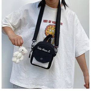 Details of the casual canvas crossbody bag featuring a contrast flap pocket and cute bear charm.