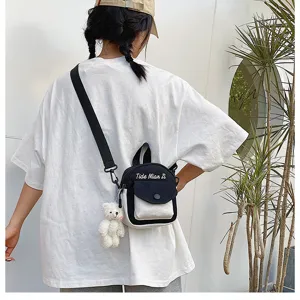 Casual canvas crossbody bag detail view with cute bear pendant and contrast color design.