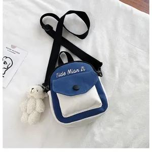 Casual contrast color canvas crossbody bag featuring a cute small bear pendant detail.