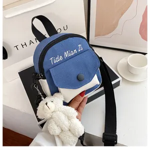 Close up view of the cute canvas crossbody bag with white pocket and adorable plush bear pendant.