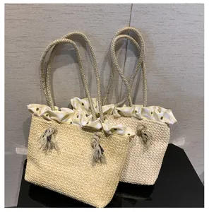 Detail shot of straw woven shoulder bag with ruffled gingham lining and tassel accents.
