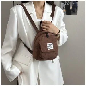 Close-up view of a brown corduroy mini backpack worn by a model, featuring front pocket.