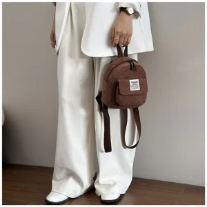 Detail shot of a brown corduroy mini backpack with cute floral prints and front pocket.