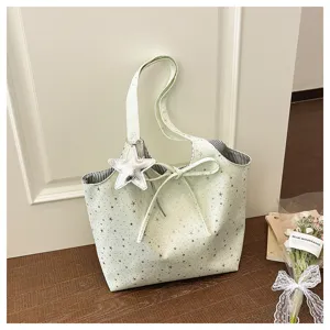 Detail view of a cute light green tote bag with silver star prints, bow tie and star pendant.
