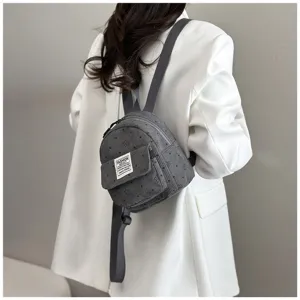 Detailed view of a stylish grey corduroy mini backpack with front pocket and shoulder straps.