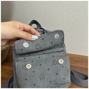 Grey corduroy mini backpack detail showing cute floral pattern and secure magnetic snap closure.