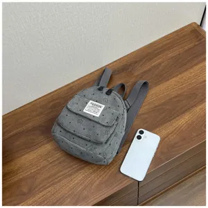 Grey corduroy mini backpack detail showing front pocket and fine woven label texture.