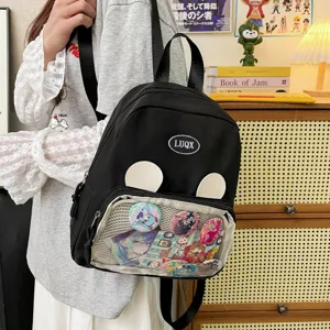 Dettaglio dello zaino ita nero con finestra trasparente, orecchie d'orso e spille anime.