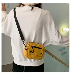 Dettaglio della borsa a tracolla in tela gialla, borsa casual compatta con tasca con zip.