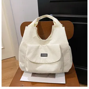 Detailed close-up of the white corduroy tote bag showing front pocket and fabric texture.