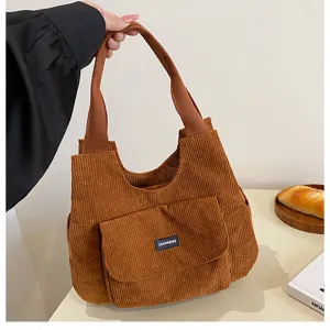 Detailed view of the brown corduroy tote bag showing front pocket and sturdy handle structure.
