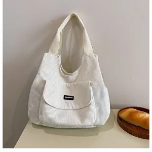 Detailed view of white corduroy tote bag showing front pocket and texture, daily commuter style.