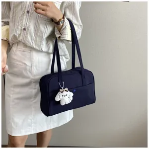 Detailed view of the dark blue shoulder bag with cute puppy plush keychain pendant.