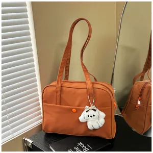 Detail view of brown casual shoulder bag with cute plush puppy charm on black surface.