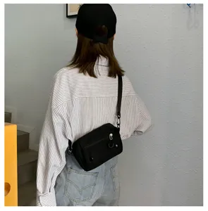 Borsa a tracolla in tela nera casual indossata dal modello, ottima per la scuola e il tempo libero.