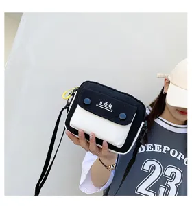 Close-up detail of stylish black and white canvas crossbody bag with contrast flap pocket.