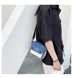 Detailed view of the stylish color-block canvas crossbody bag worn by the model outdoors.
