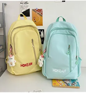 Detail view of large capacity Japanese style solid color school backpack with bear pendant.