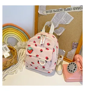 Detail shot of pink corduroy strawberry print mini backpack with cute front patch and straps.