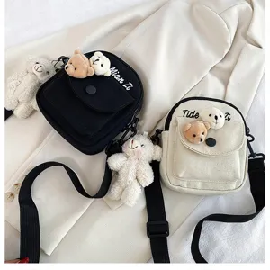 Canvas crossbody bag with cute plush bear pendant and letter print for women fashion style.