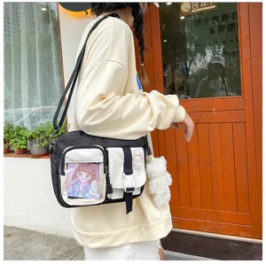 Détail de sac bandoulière en toile avec multi-poches, fente transparente et charm peluche.