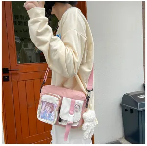 Sac bandoulière en toile rose avec plusieurs poches, fenêtre transparente et charm.
