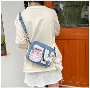 Vue détaillée du sac bandoulière élégant en toile avec poche transparente et pendentif.