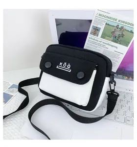 Detailed view of the black and white canvas crossbody bag with flap and metal snaps.