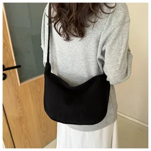 Detail shot of the black corduroy shoulder bag, showing slouchy crescent shape and fine strap.