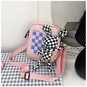 Pink canvas crossbody bag detail, cute checkered rabbit plush pendant, casual daily style.