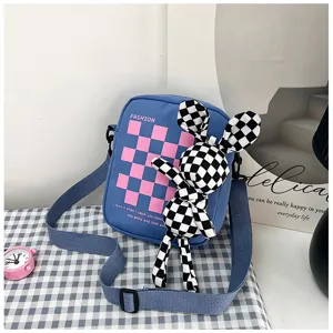 Detailed view of blue checkerboard canvas crossbody bag with cute plush rabbit doll pendant.