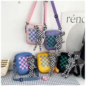 Canvas cross body bag detail showing vibrant checkered pattern and cute rabbit plush pendant.