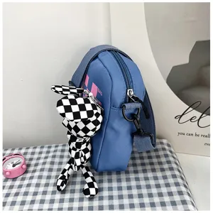 Blue canvas crossbody bag detail shot featuring a stylish checkered rabbit plush charm and strap.