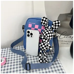 Canvas crossbody bag detail showing pink checkerboard pattern and cute bunny plush toy pendant.