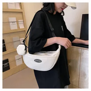 Detailed shot of a stylish white crescent crossbody bag with a small pouch and black strap.